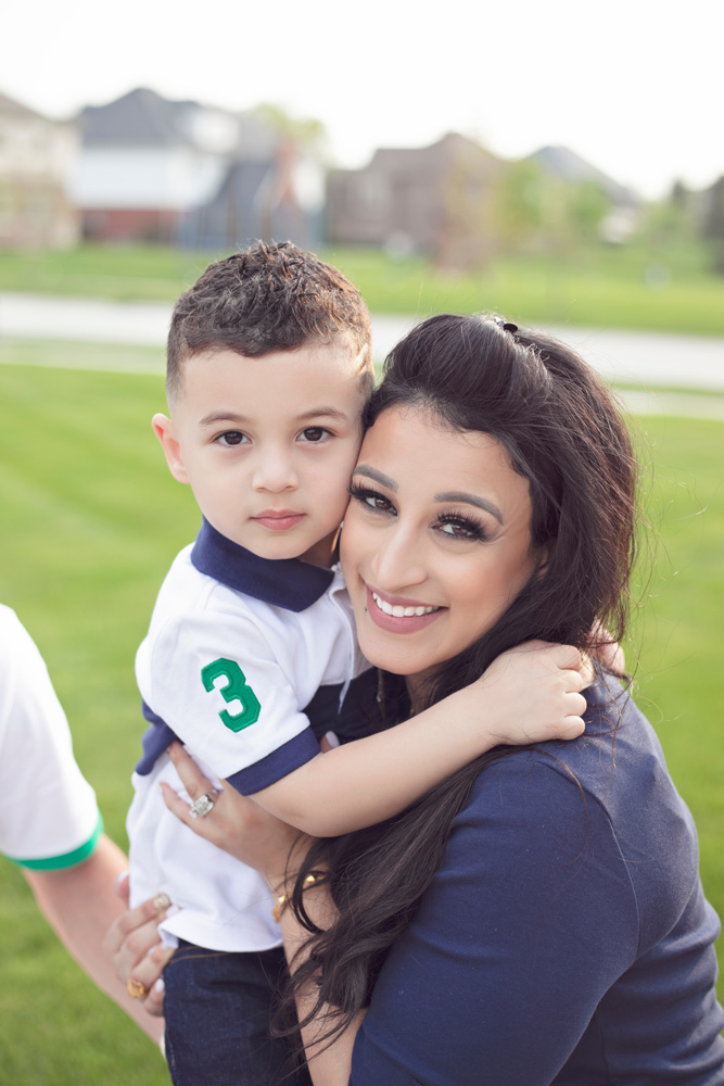Sabreen Rihan holding her son Adriyan Isa in her arms outdoors.