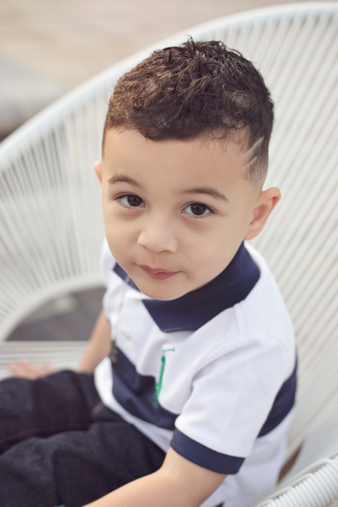 Adriyan Isa sitting in a white woven chair outdoors.