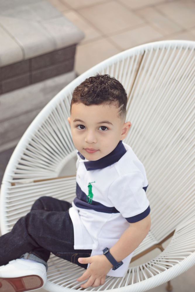 Adriyan Isa sitting in a white woven chair outdoors.