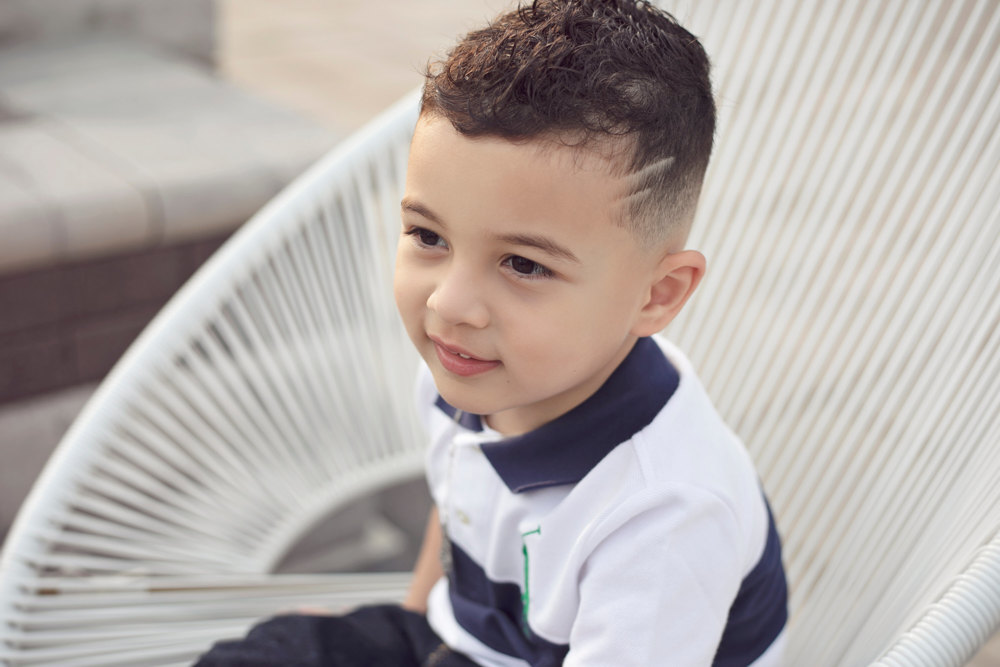 Adriyan Isa sitting in a white woven chair outdoors.