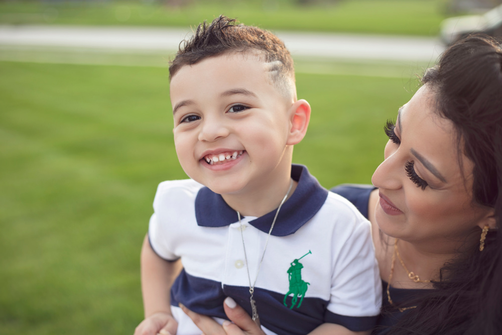 Adriyan Isa smiling beside his mother Sabreen Rihan outdoors.