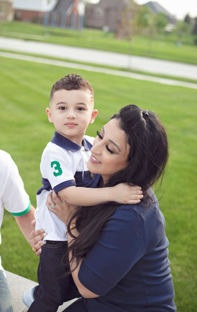 Sabreen Rihan holding her son Adriyan Isa in her arms outdoors.