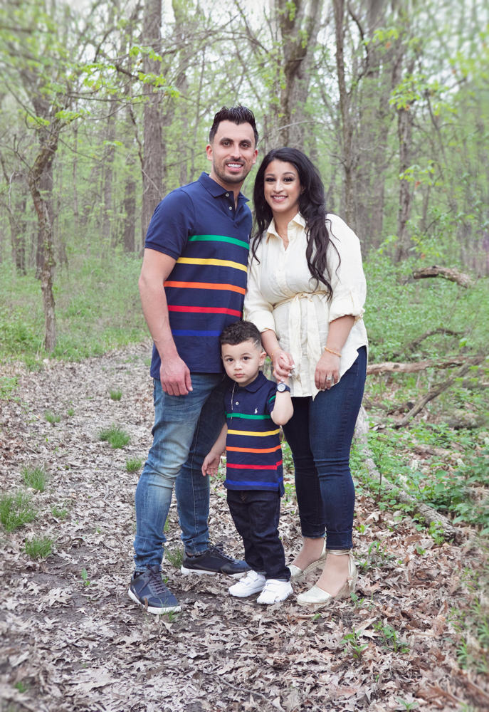 Firas Isa and Sabreen Rihan posing with their son Adriyan Isa among the trees.