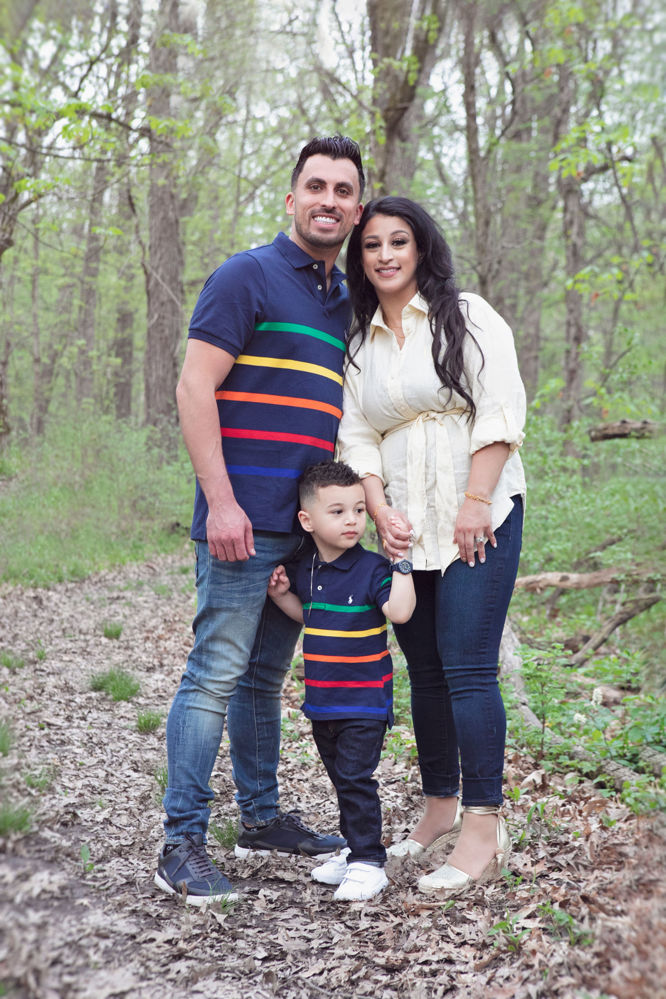 Firas Isa and Sabreen Rihan posing with their son Adriyan Isa among the trees.