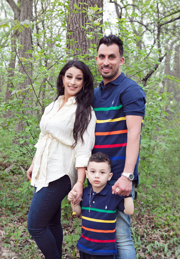 Firas Isa and Sabreen Rihan posing with their son Adriyan Isa among the trees.