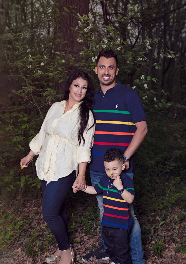 Firas Isa and Sabreen Rihan posing with their son Adriyan Isa among the trees.