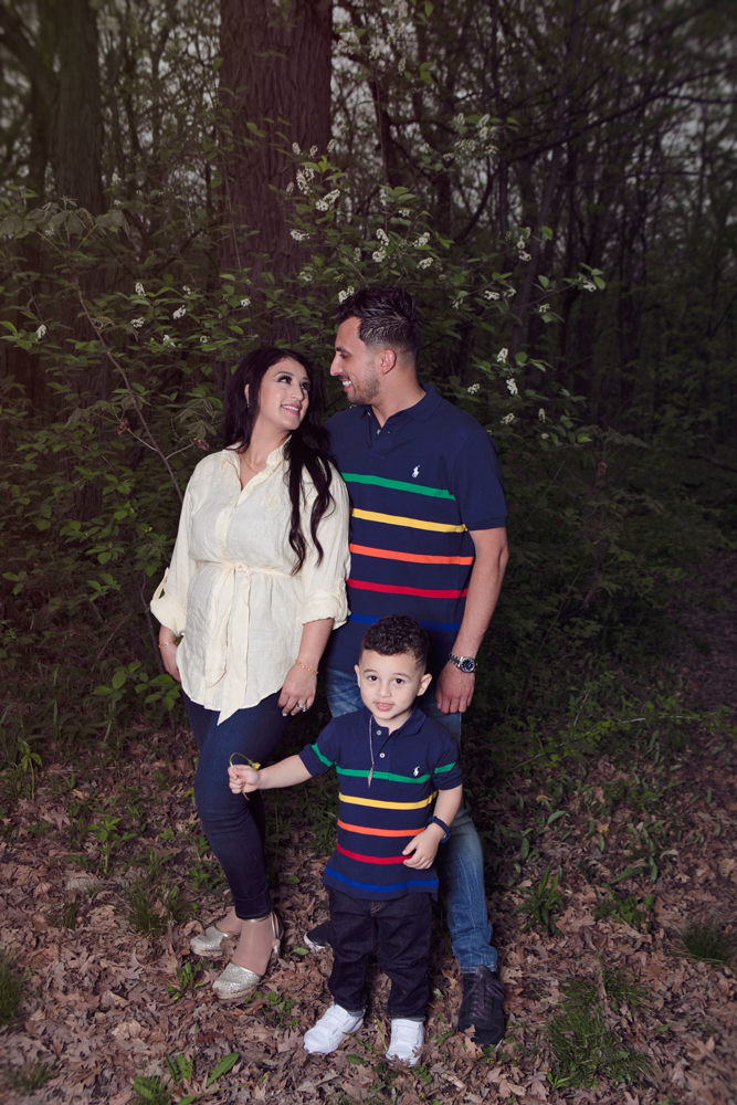 Firas Isa kissing his wife Sabreen Rihan as their son Adriyan Isa stands beside them in the woods.