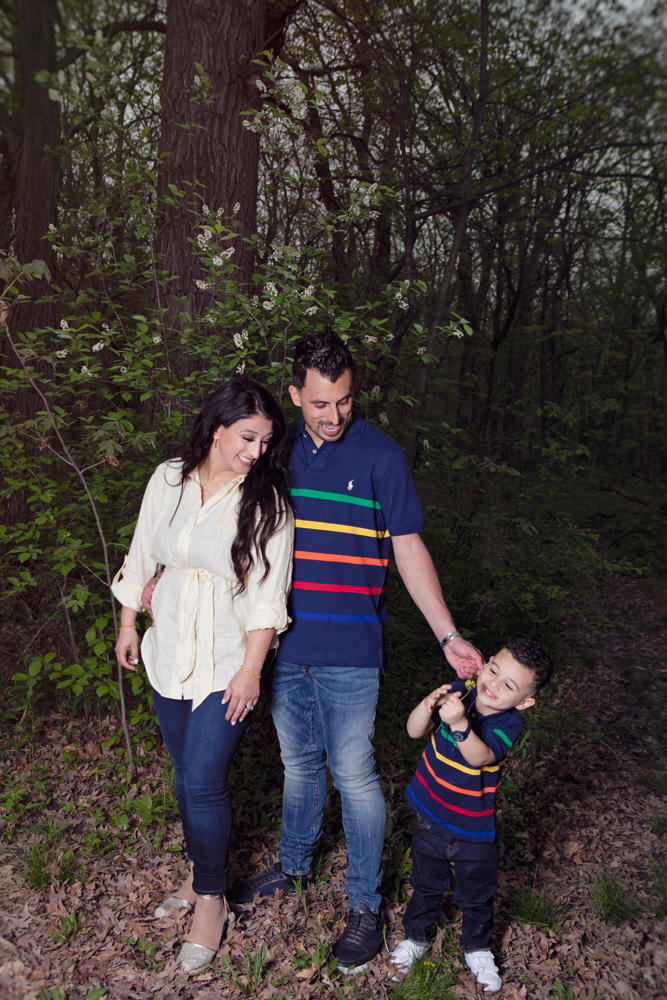Firas Isa and Sabreen Rihan posing with their son Adriyan Isa among the trees.
