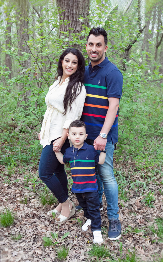 Firas Isa and Sabreen Rihan posing with their son Adriyan Isa among the trees.