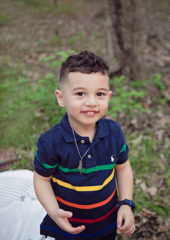 Adriyan Isa smiling while standing among the trees.