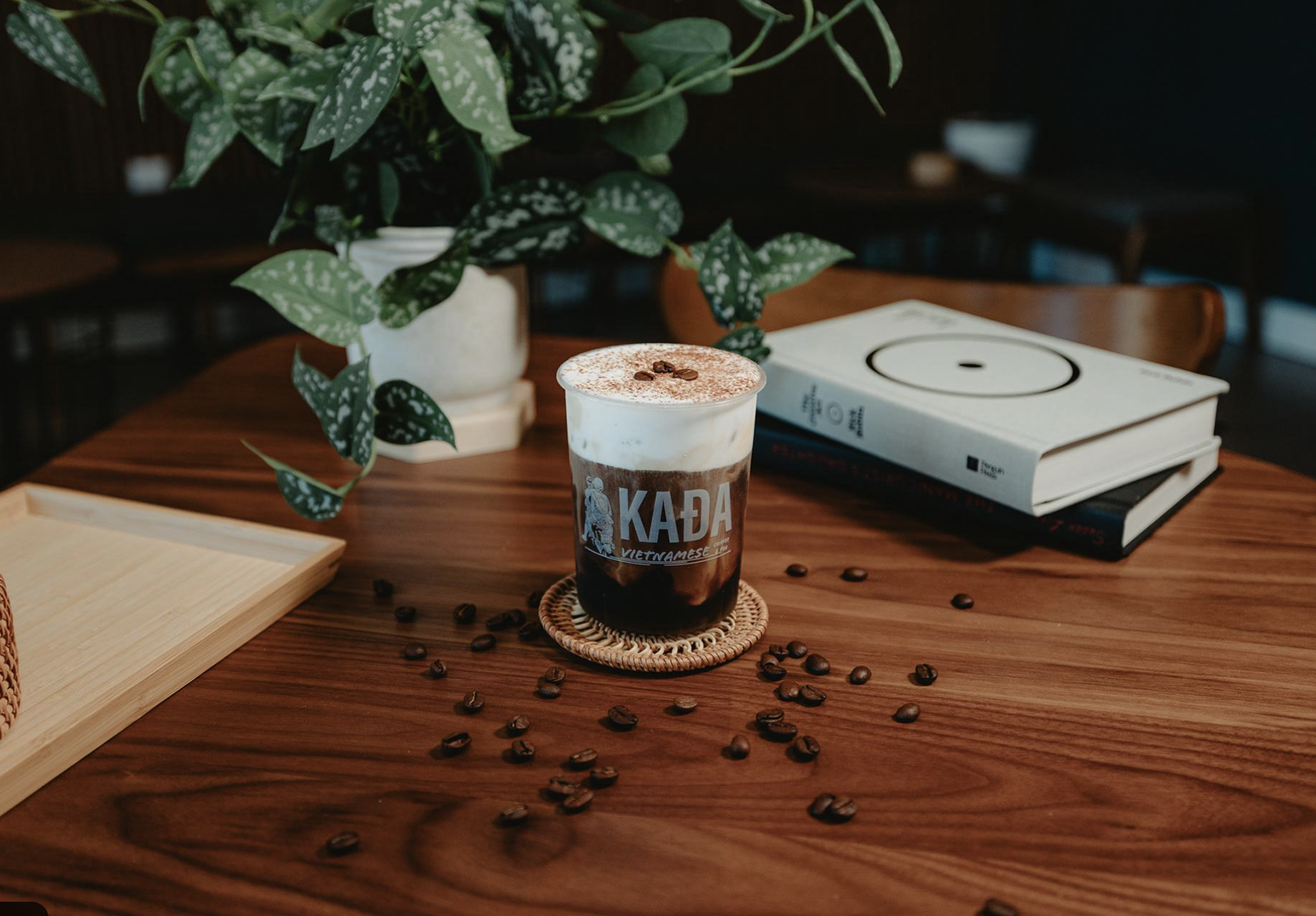 Vietnamese coffee in a KAĐA cup surrounded by whole coffee beans