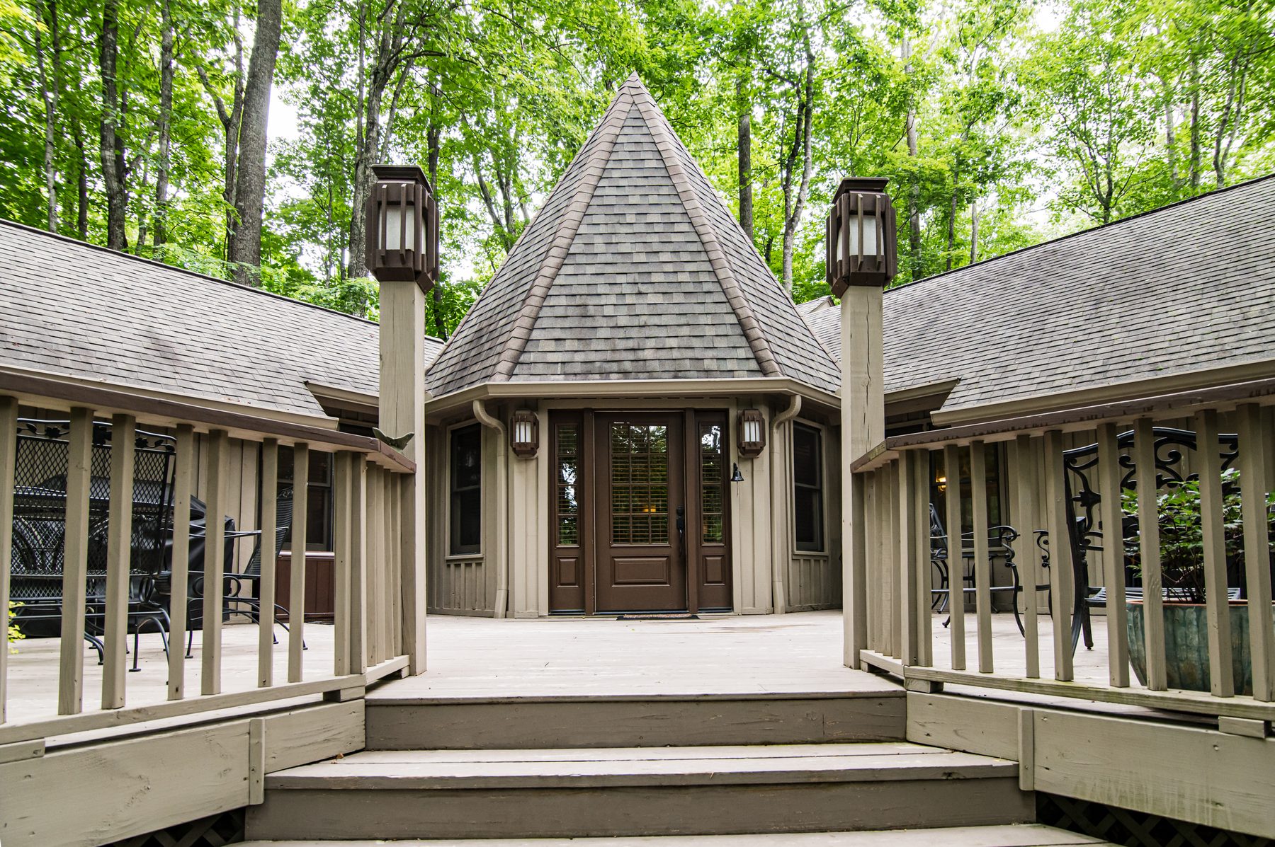 Front entrance of the cottage framed by lantern-topped posts and the conical turret roof