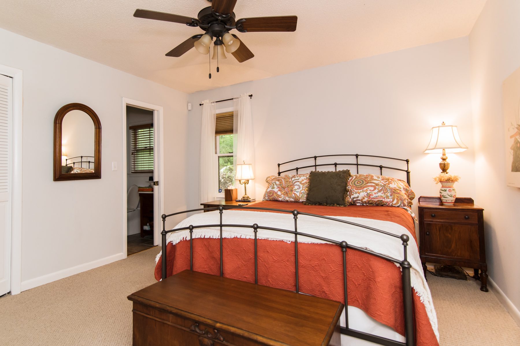 Queen bedroom with an iron bed, warm bedding and an en-suite bathroom