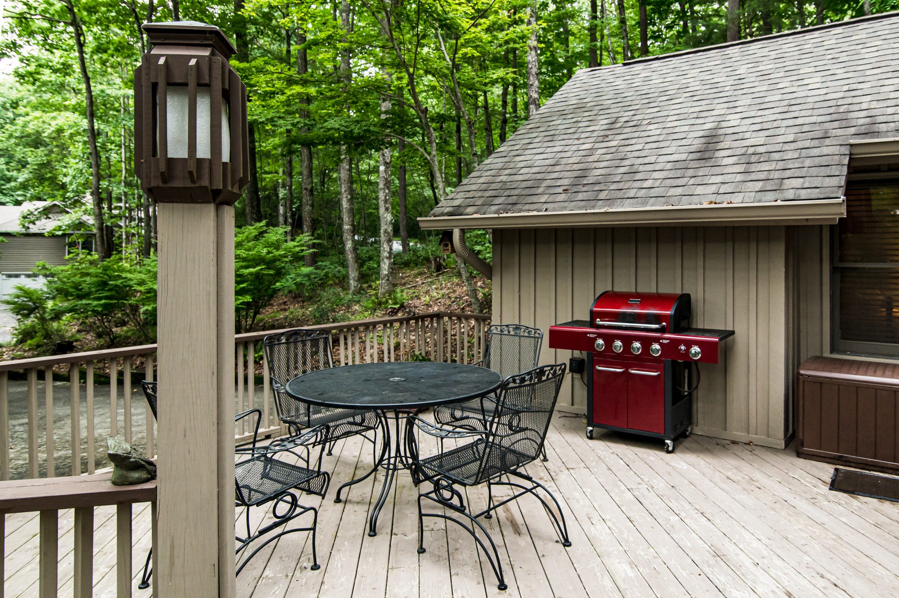 Back deck with a gas grill and a patio dining set among the trees