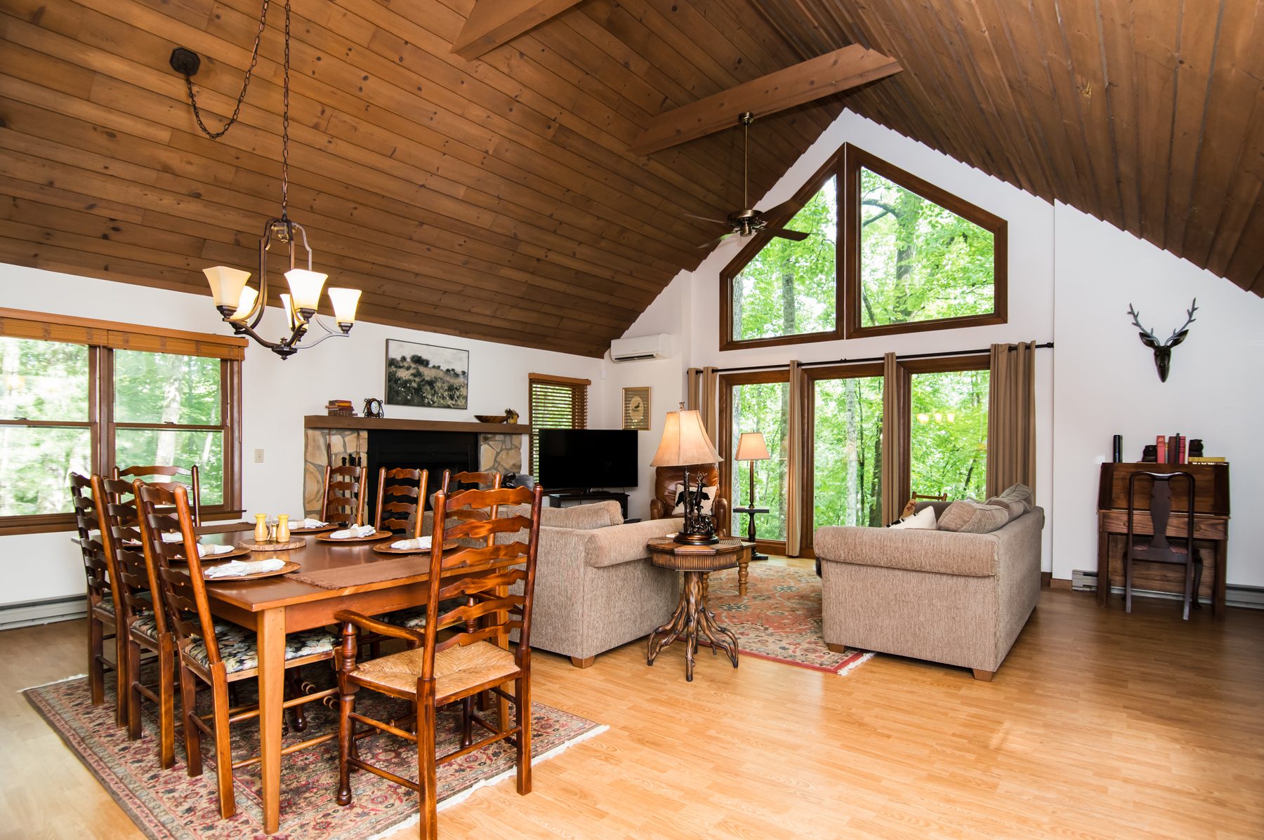 Vaulted living and dining room with a wall of windows overlooking the trees