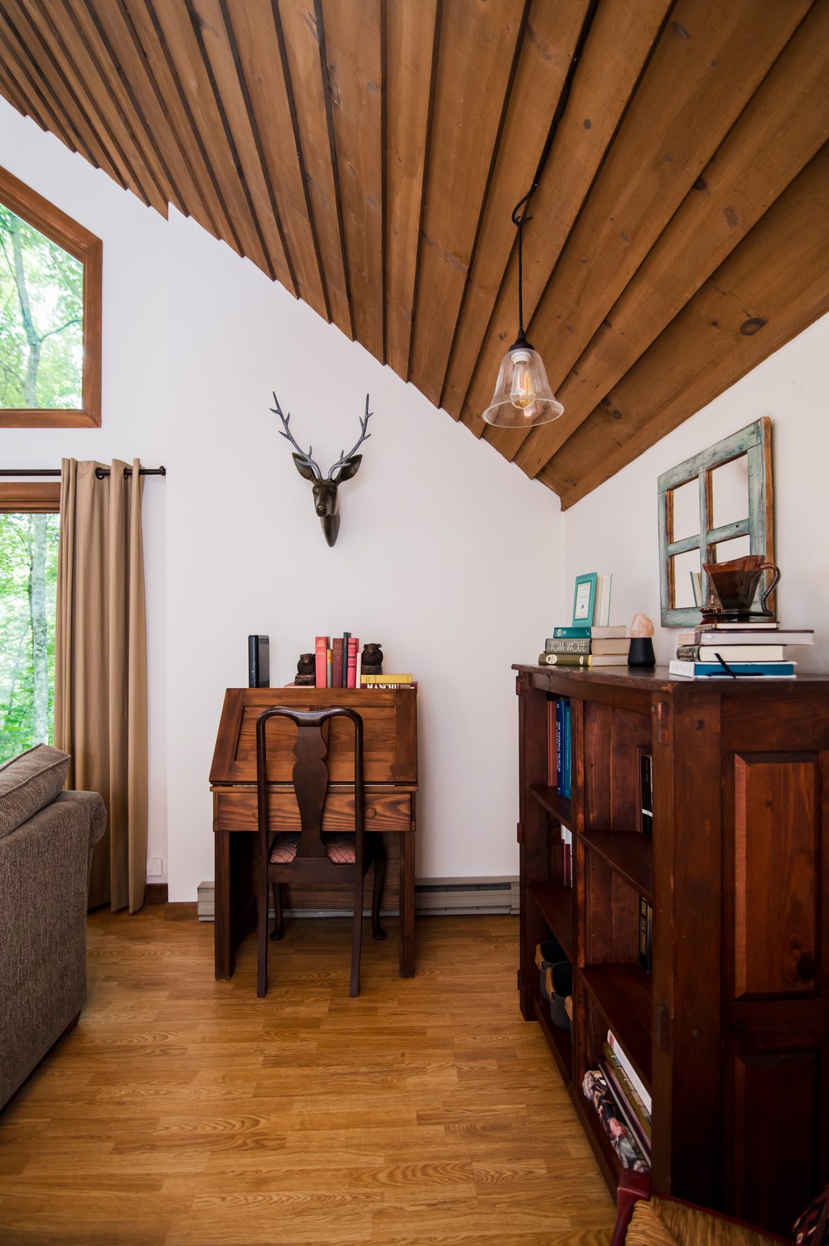Cozy reading and writing nook with an antique desk, bookshelf and mounted stag head