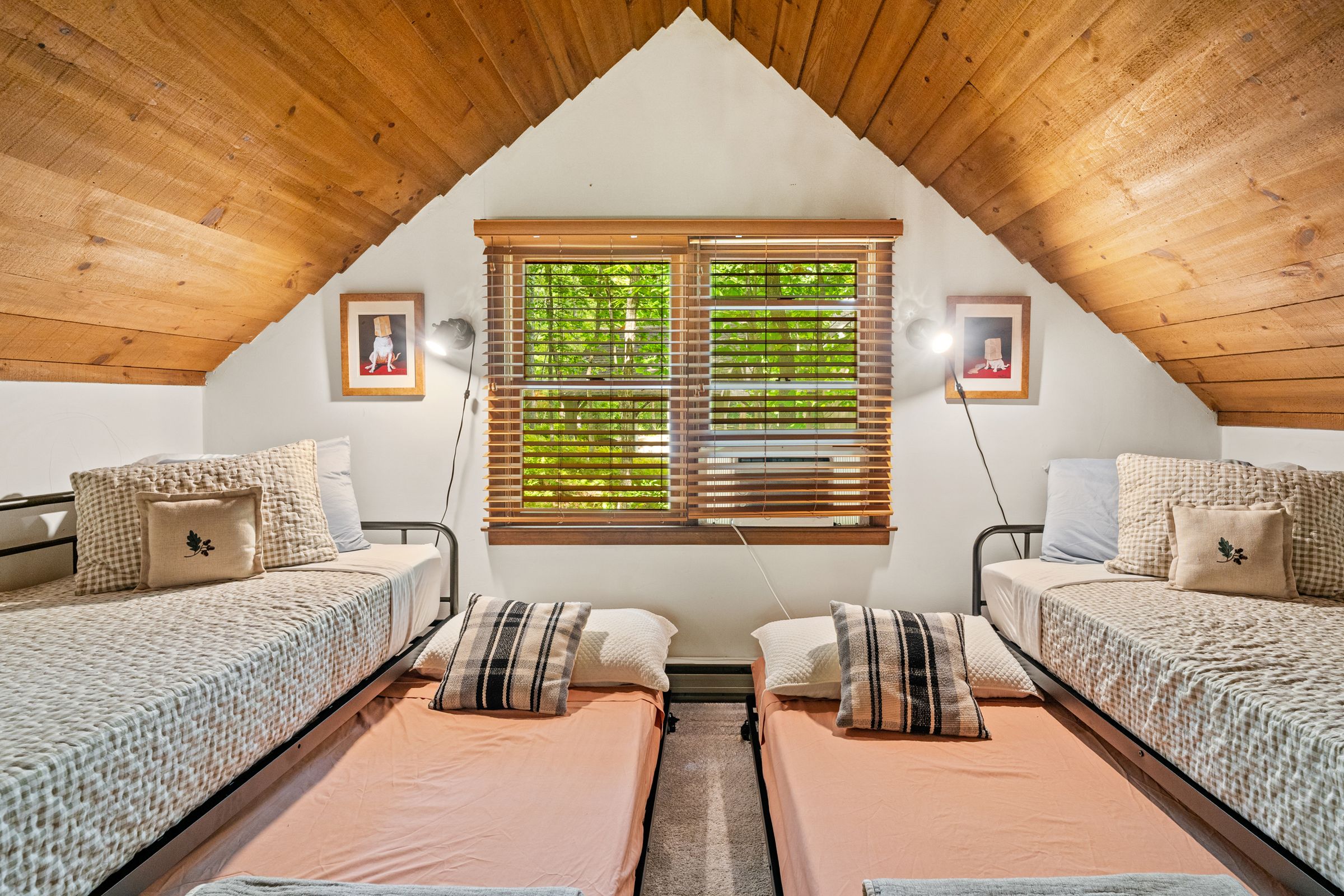 The loft under a pine ceiling, with twin beds and pillows ready for kids
