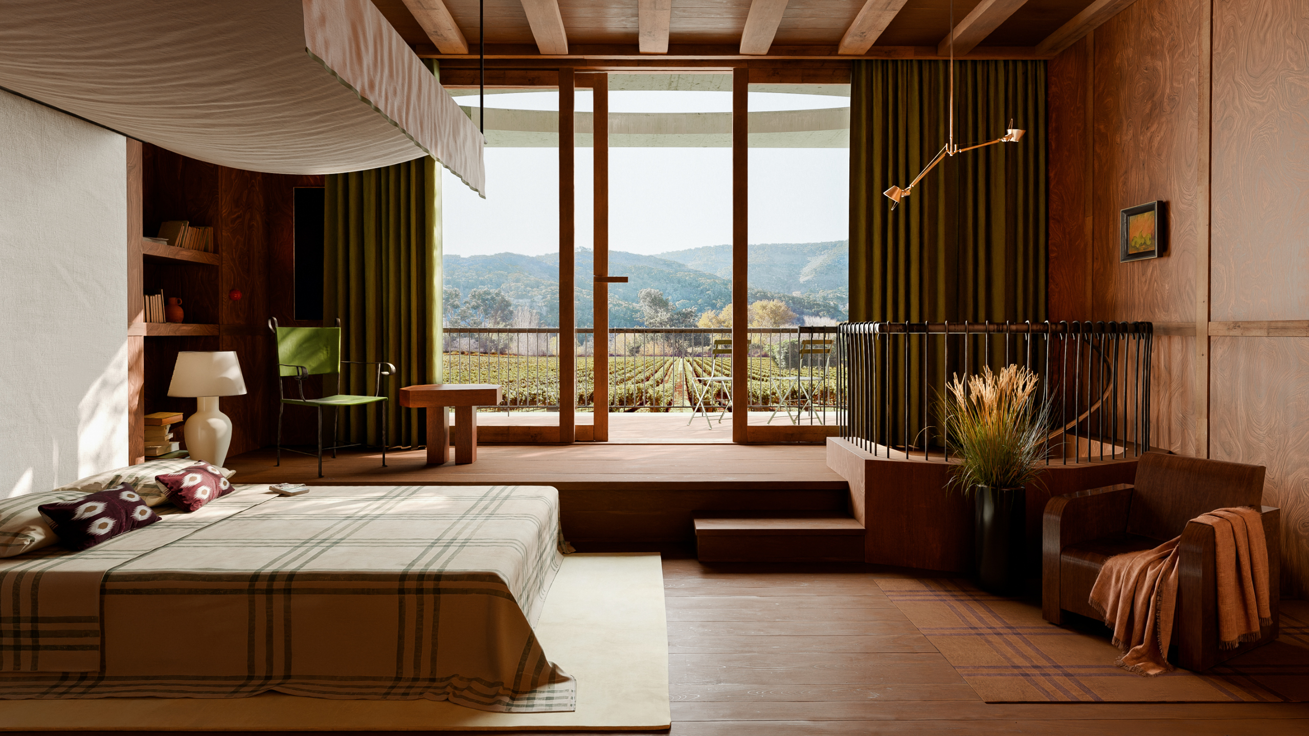 A wood-toned bedroom with low bed, seating area, and large windows overlooking a lush green field.