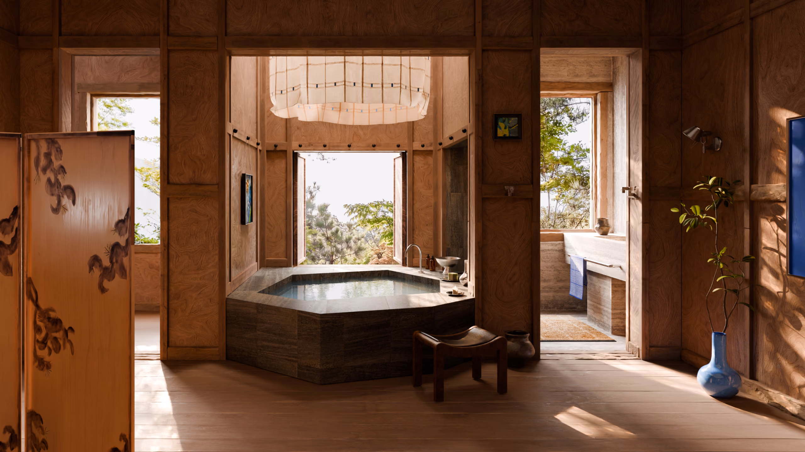 A bathroom with a large stone bathtub under a skylight overlooks a garden outside.