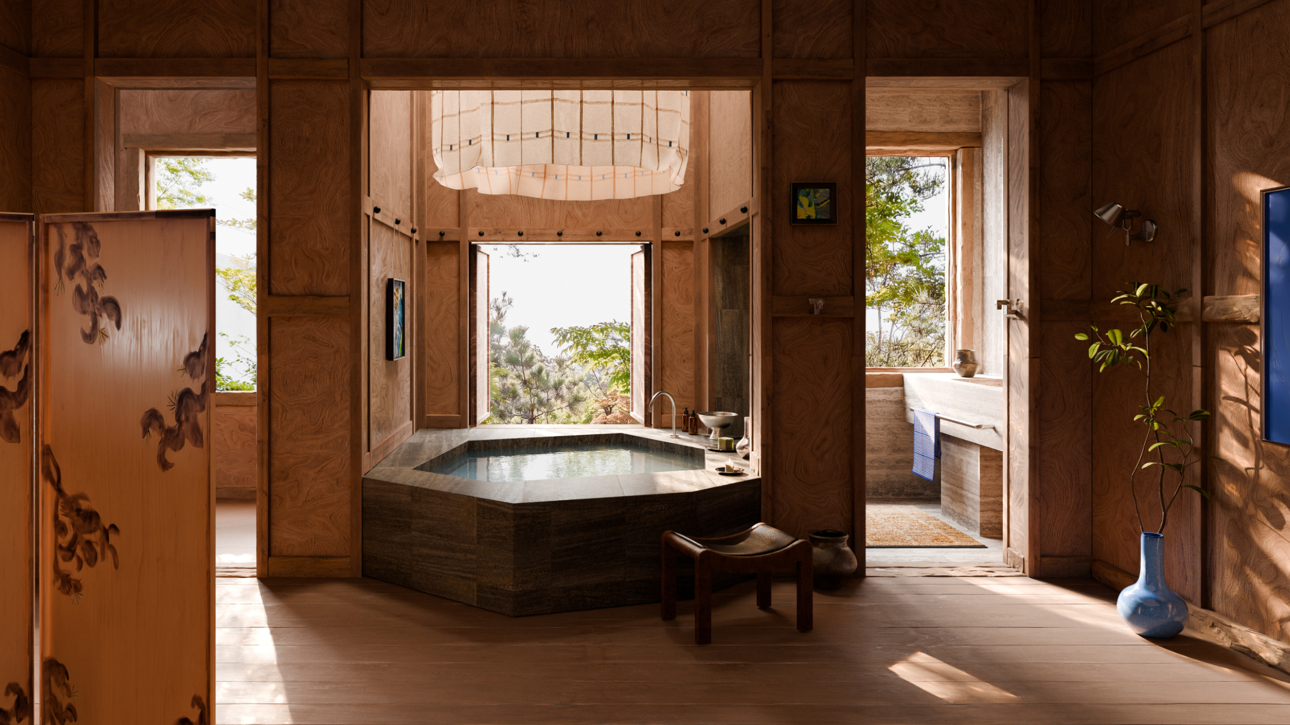 A bathroom with a large stone bathtub under a skylight overlooks a garden outside.