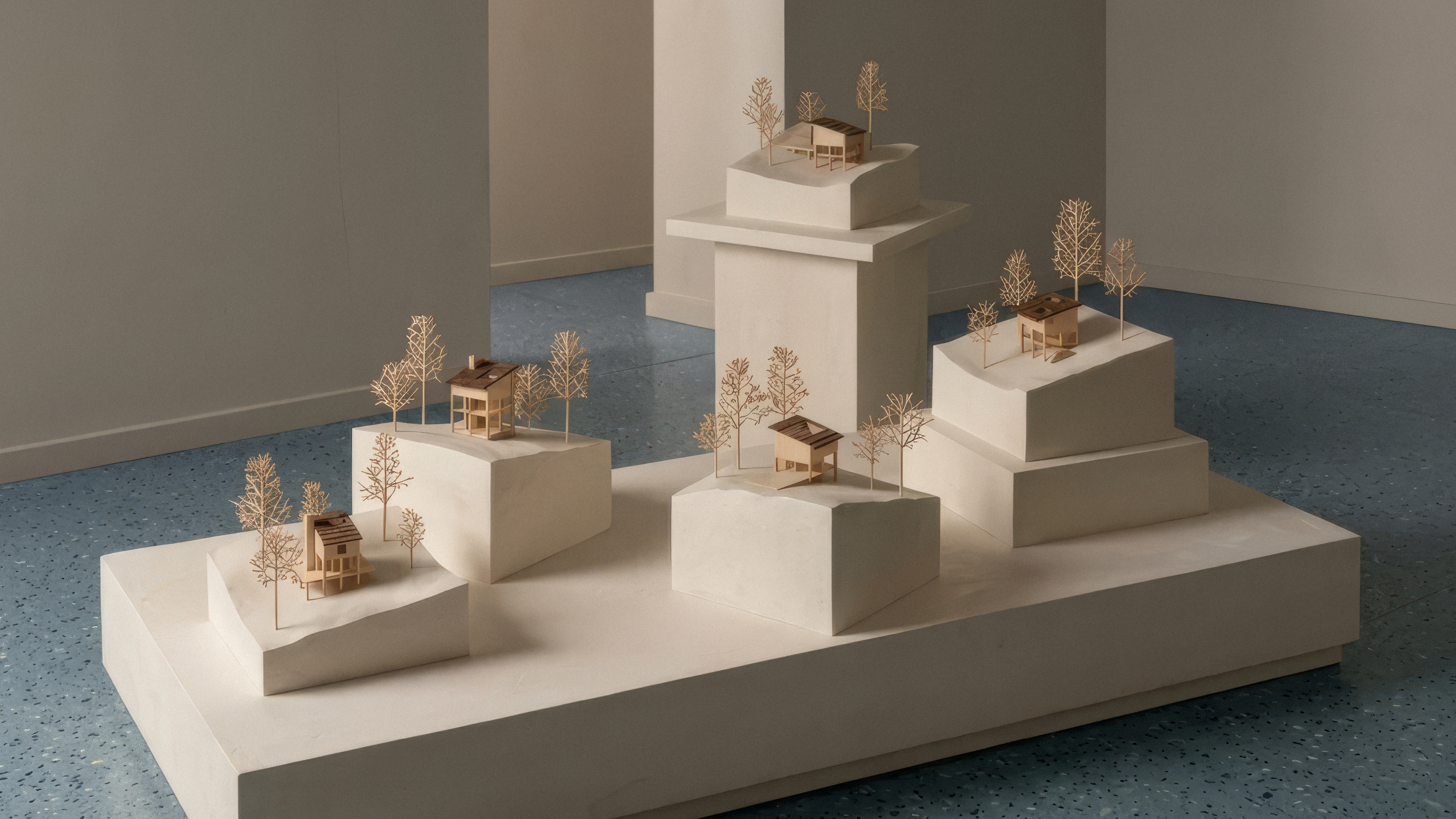 Five architectural models, all sitting on the same wood plinth, of cabins and their individual terrains.