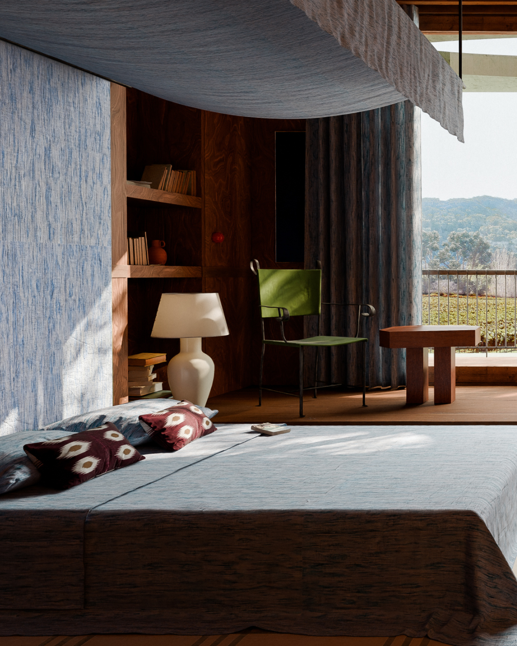 Minimalist bedroom with blue bedspread, patterned pillows, white lamp, green chair, and balcony with scenic mountain view.