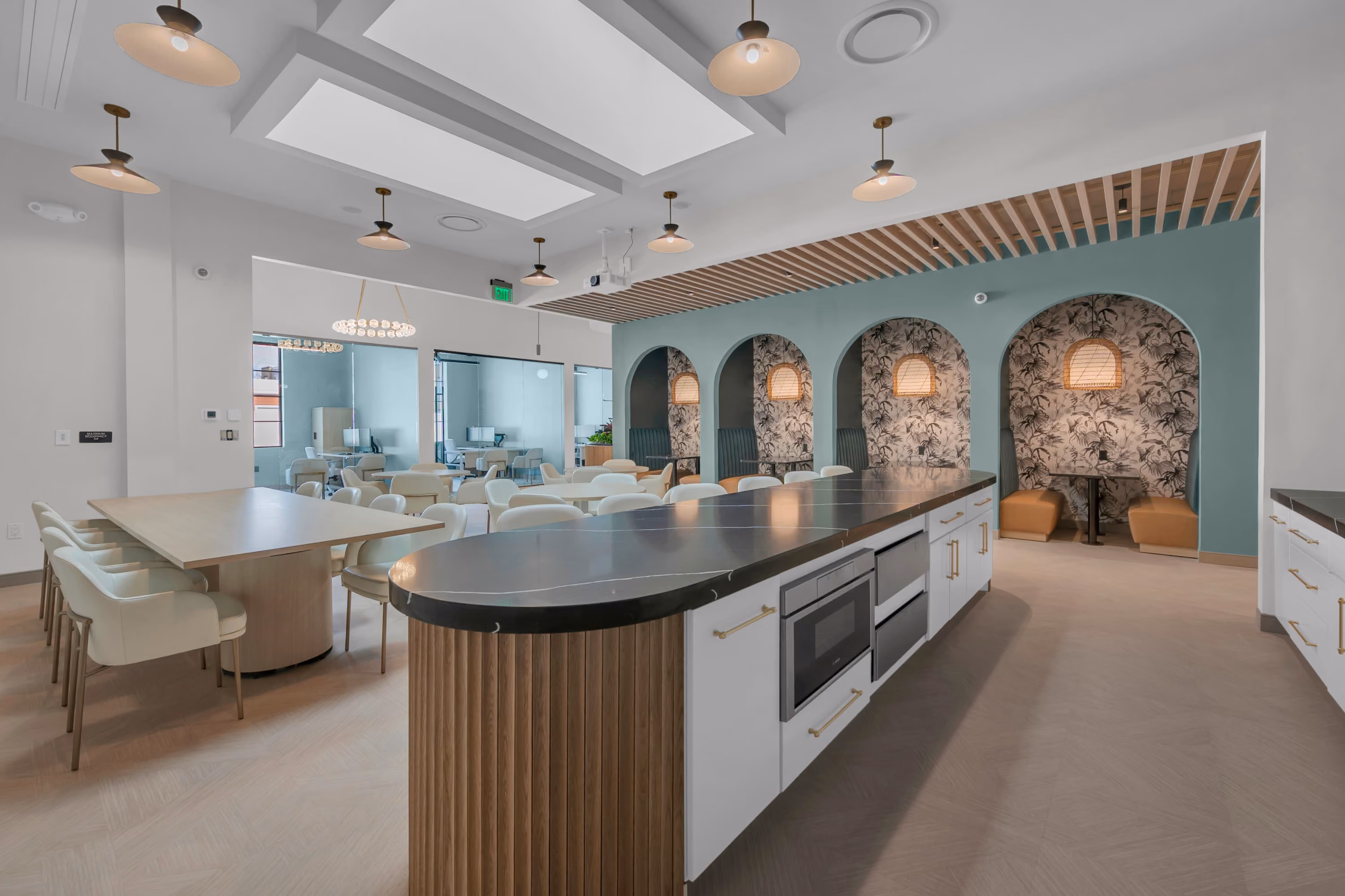 Modern dining area with a large island, cream chairs, and semi-private booths with patterned walls.