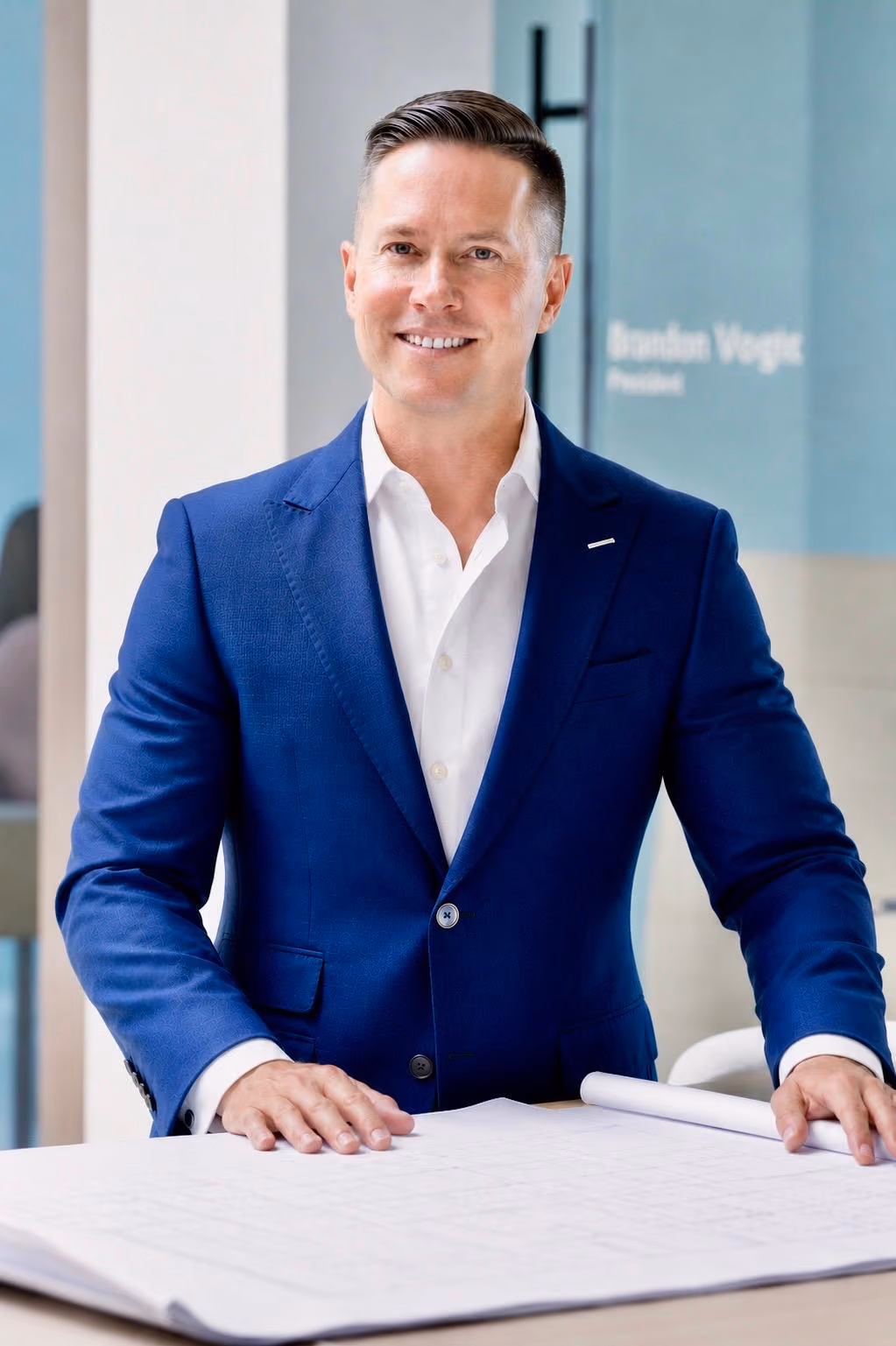 Mitch Painter leaning over property blueprints and architectural plans at Prestige Properties