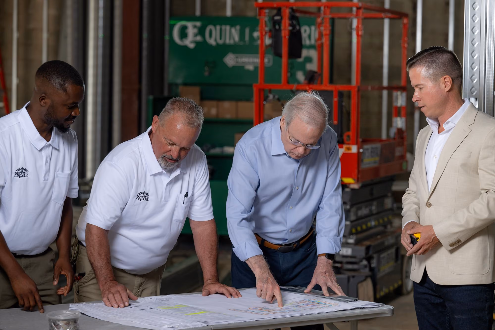 Mitch Painter and Prestige construction team reviewing architectural blueprints on a job site