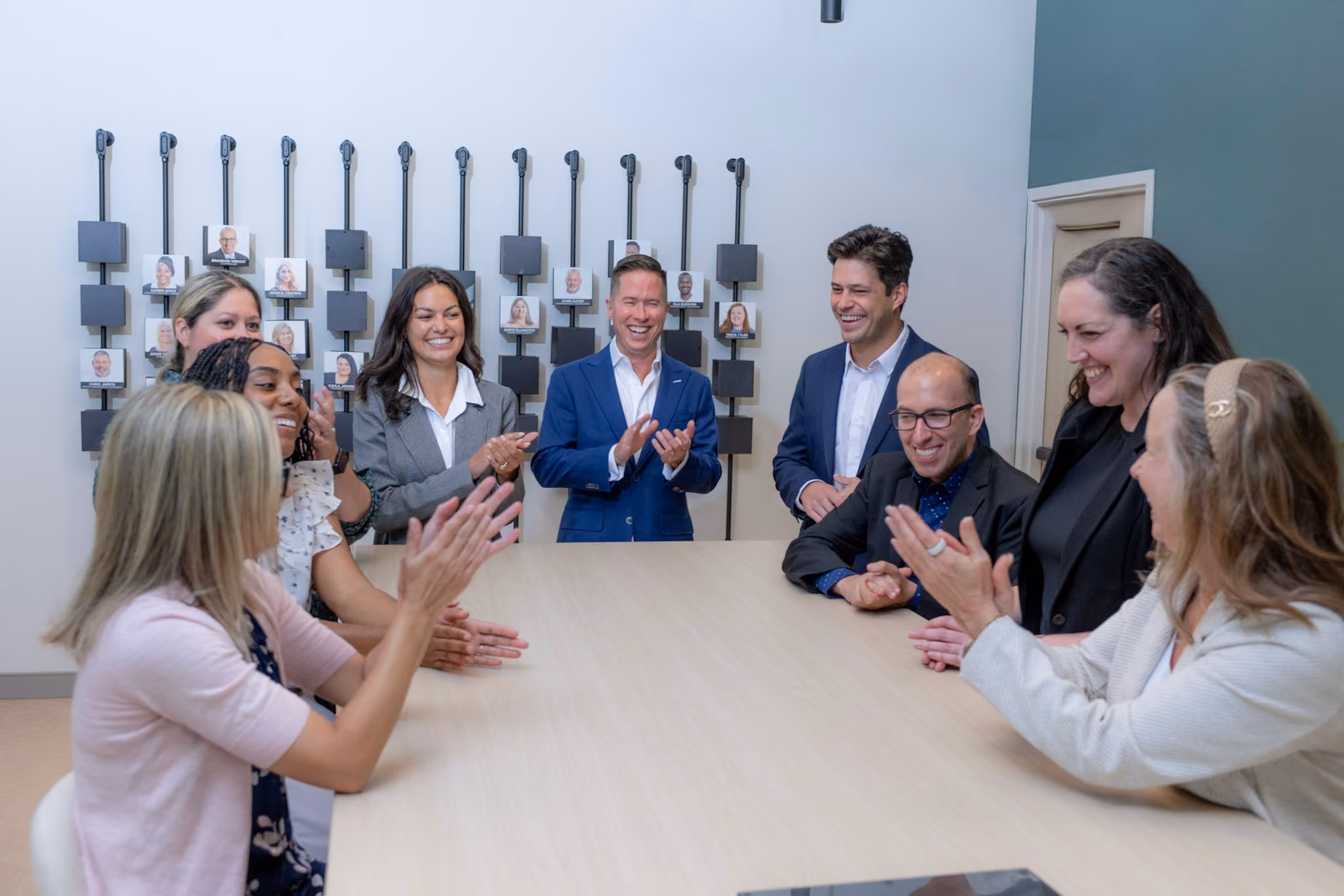 Mitch Painter and Prestige Properties team members applauding around a conference room table