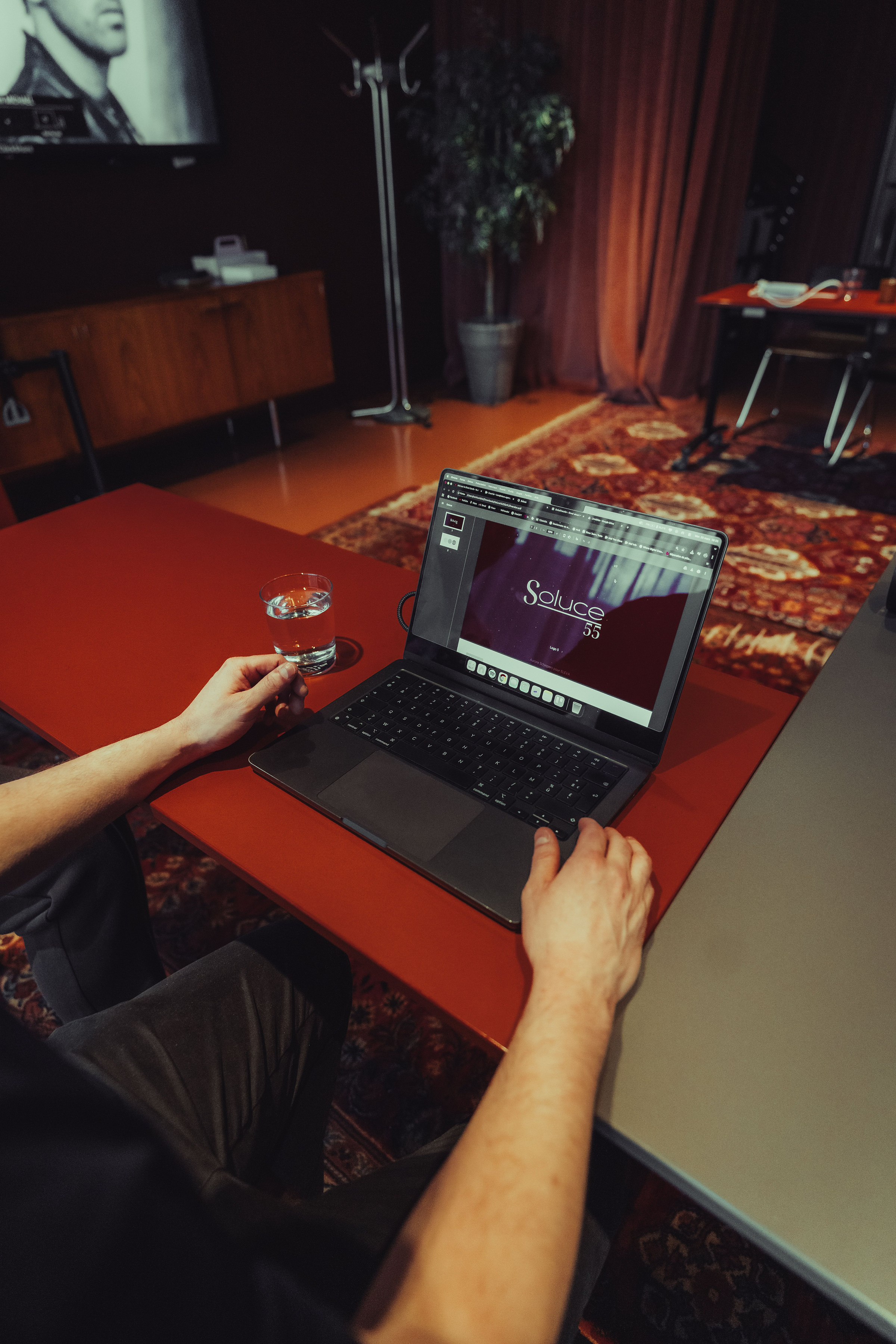 Mains sur un ordinateur portable affichant le logo Soluce 55, sur une table rouge