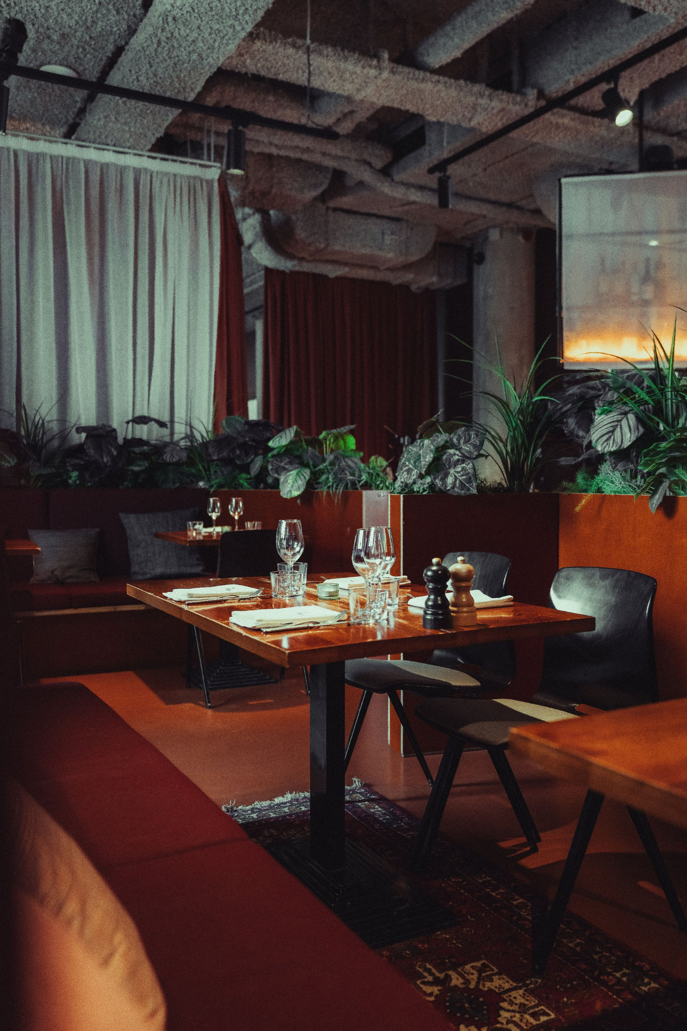 Table de restaurant parfaitement dressée, verres, serviettes et moulins, banquette rouge