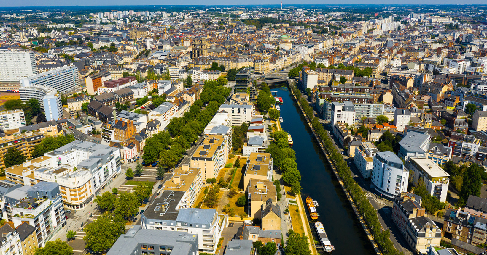 Vue aérienne de la ville avec un canal bordé d'immeubles résidentiels et bâtiments historiques.