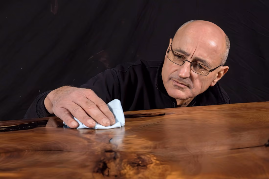 Tischlermeister Beaupoil in seinem Atelier beim Veredeln und Ölen einer Tischplatte eines hochwertigen Collectible Möbels und Designobjektes