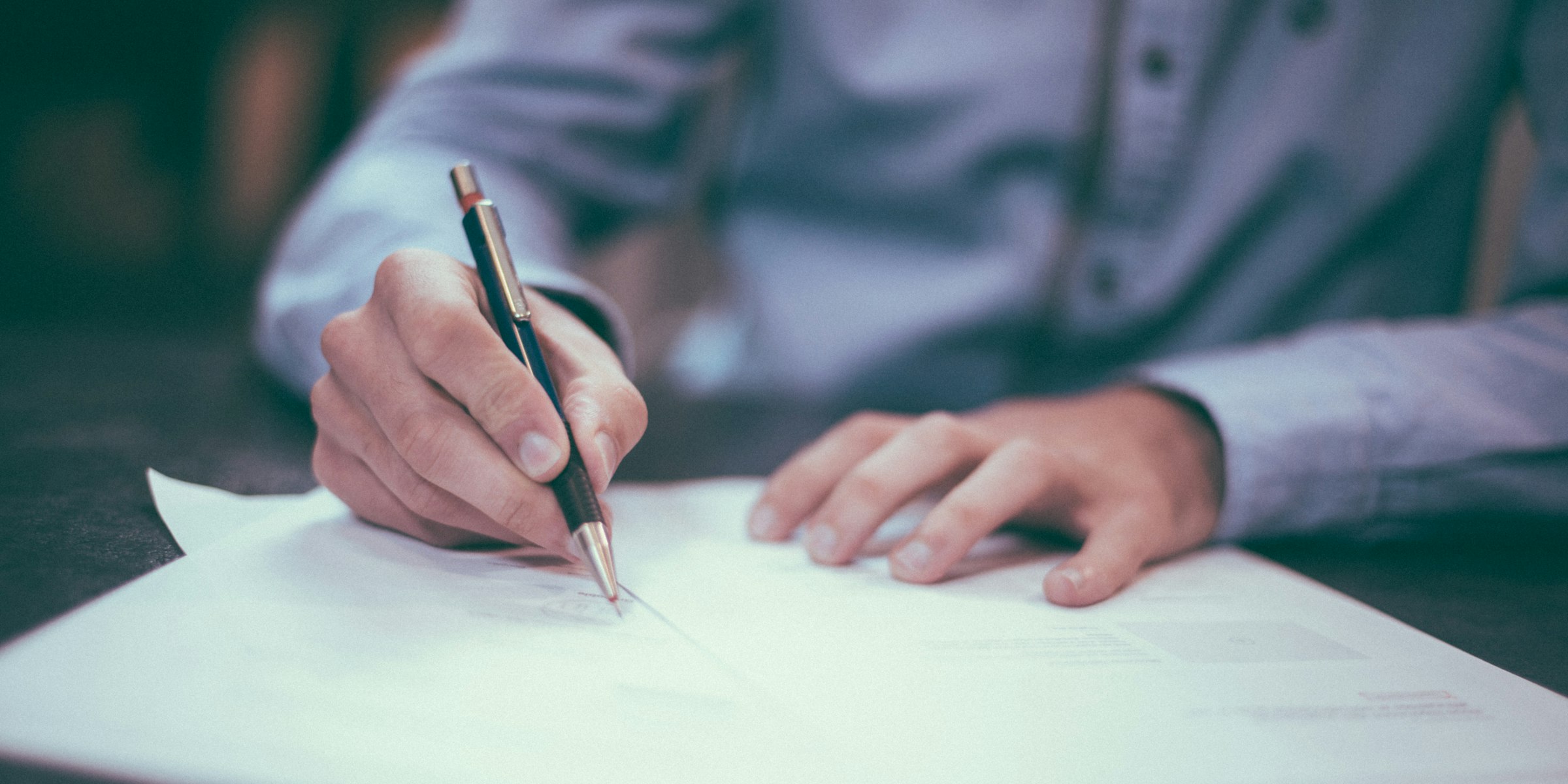 Person unterschreibt einen Immobilienkaufvertrag, Symbolbild für den rechtlichen Ablauf beim Immobilienverkauf im Allgäu (Foto: Scott Graham / Unsplash)