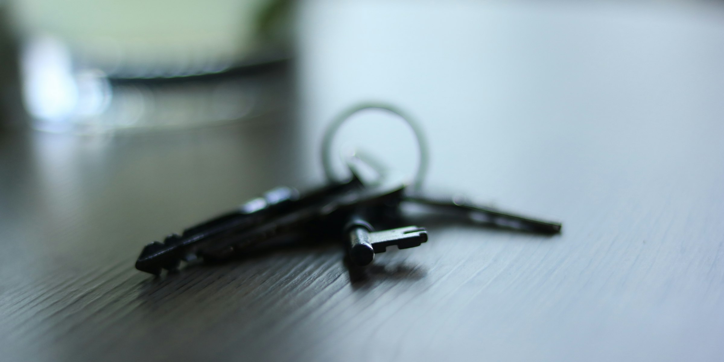 Hausschlüssel liegen einsam auf einem Tisch in einem stillen Zimmer, Symbolbild für den Hausverkauf bei Scheidung im Allgäu (Foto: Alicia Christin Gerald / Unsplash)