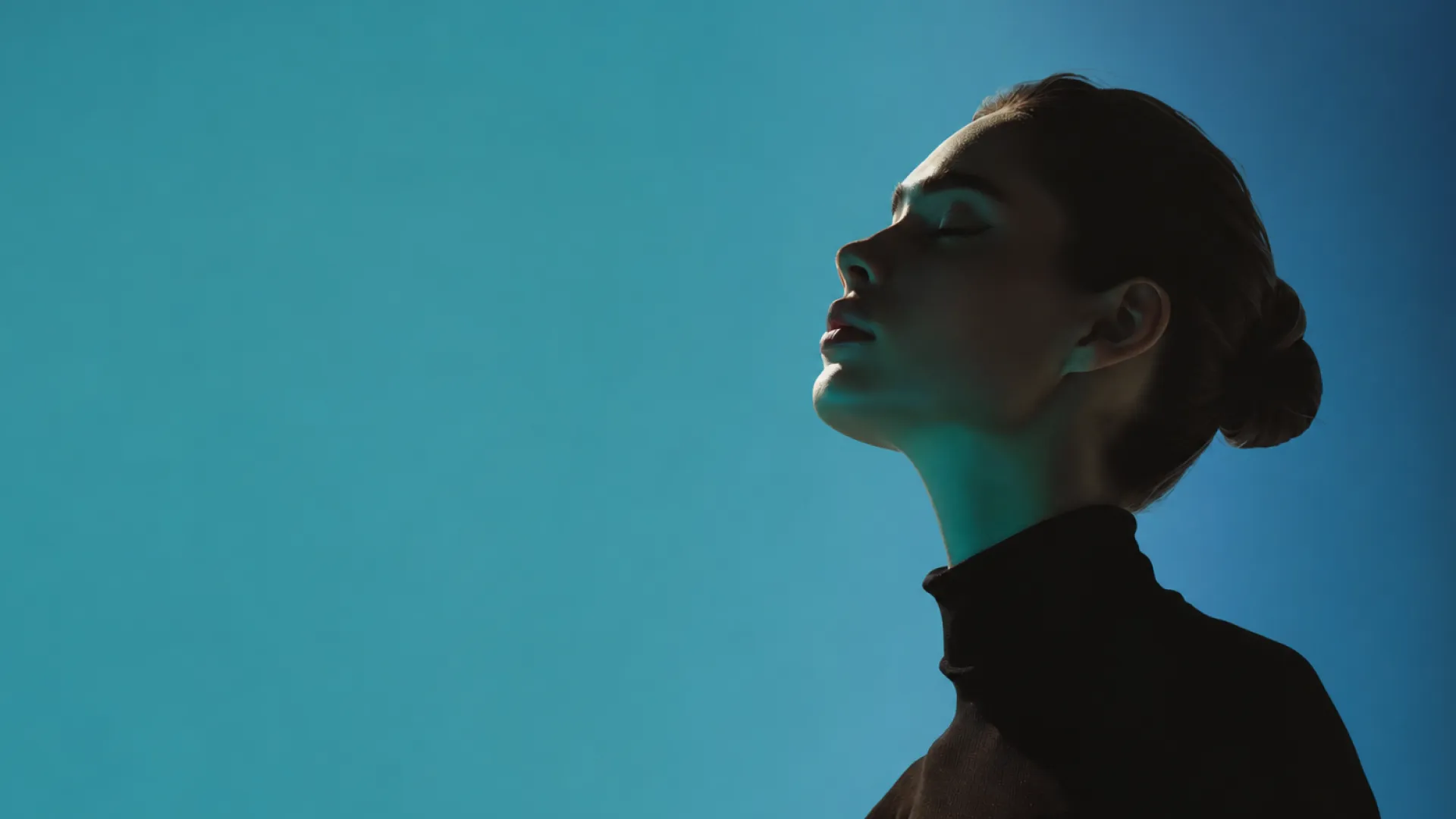 Woman in profile with eyes closed against a teal background