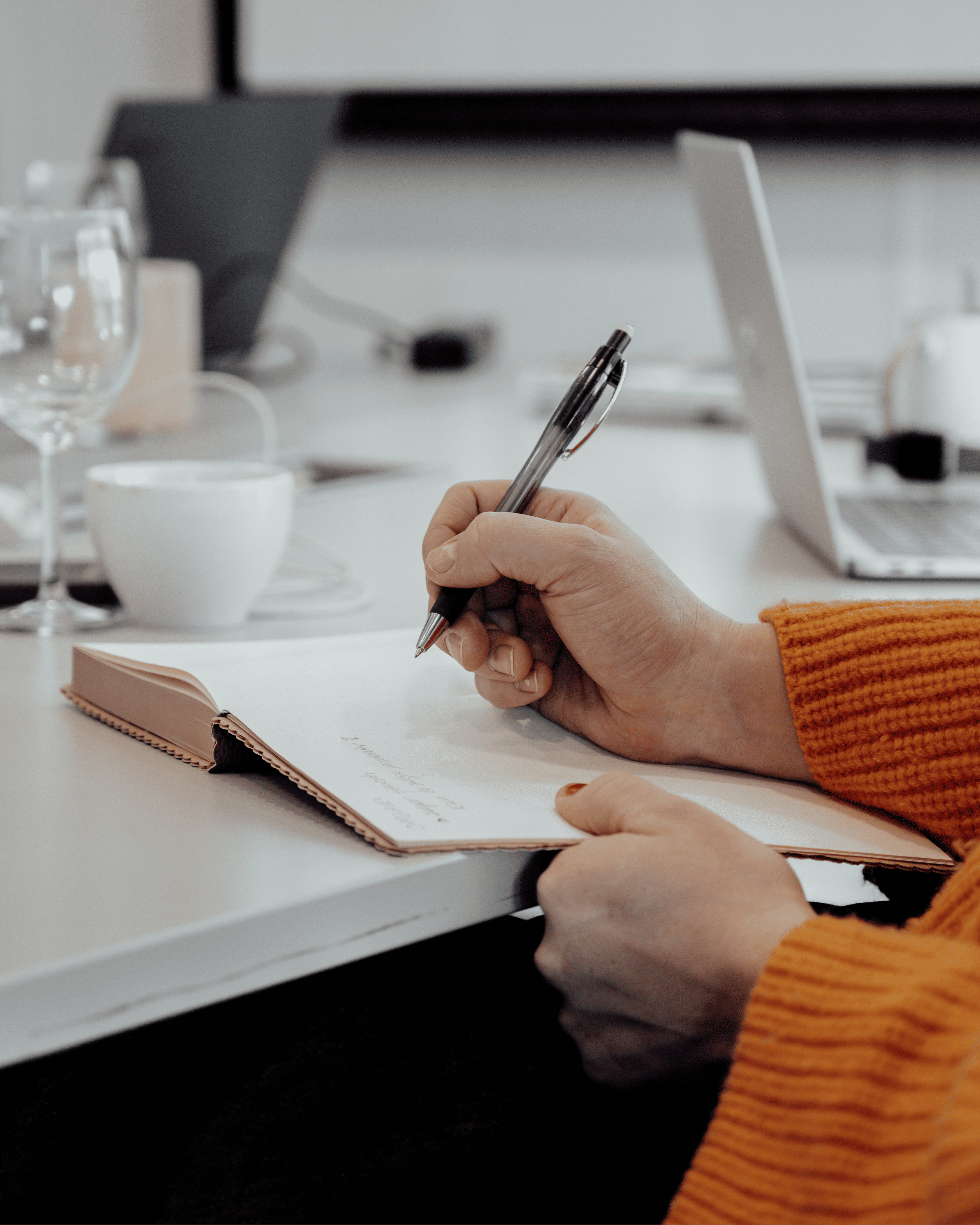 Person taking notes in a notebook at a desk