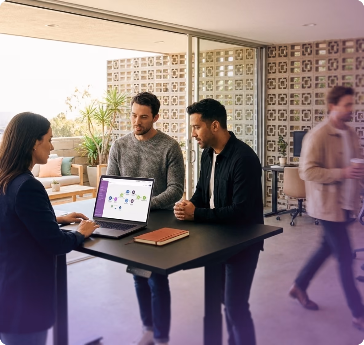 Team gathered around a laptop at a standing desk