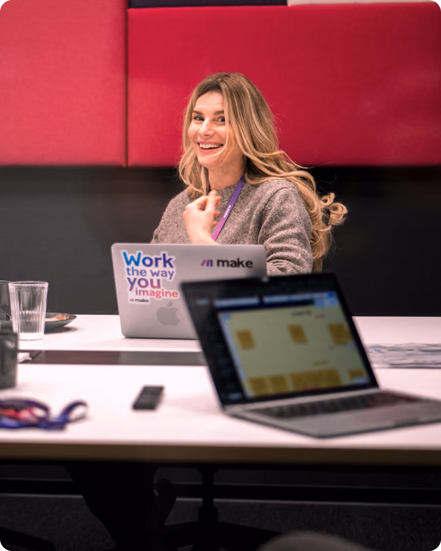 Designer smiling at a laptop in a meeting room