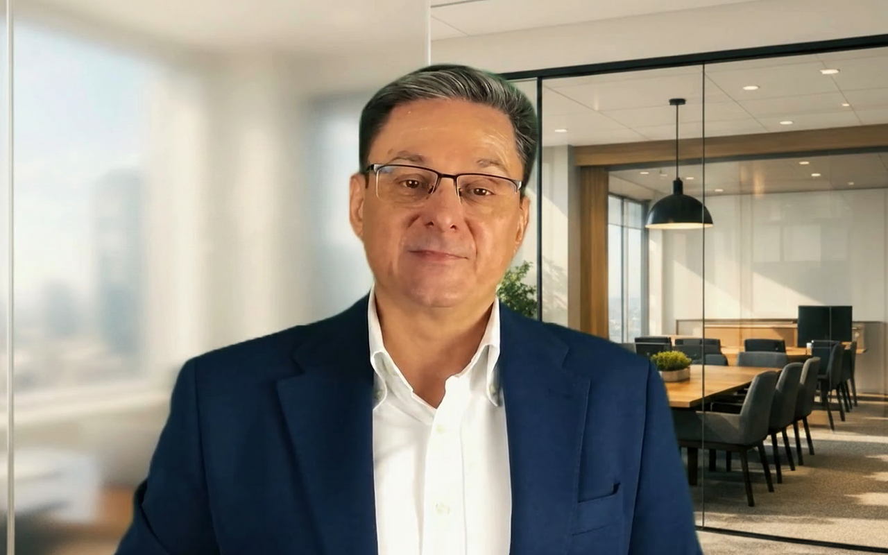 Middle-aged man wearing glasses and a navy blazer in a modern office conference room.