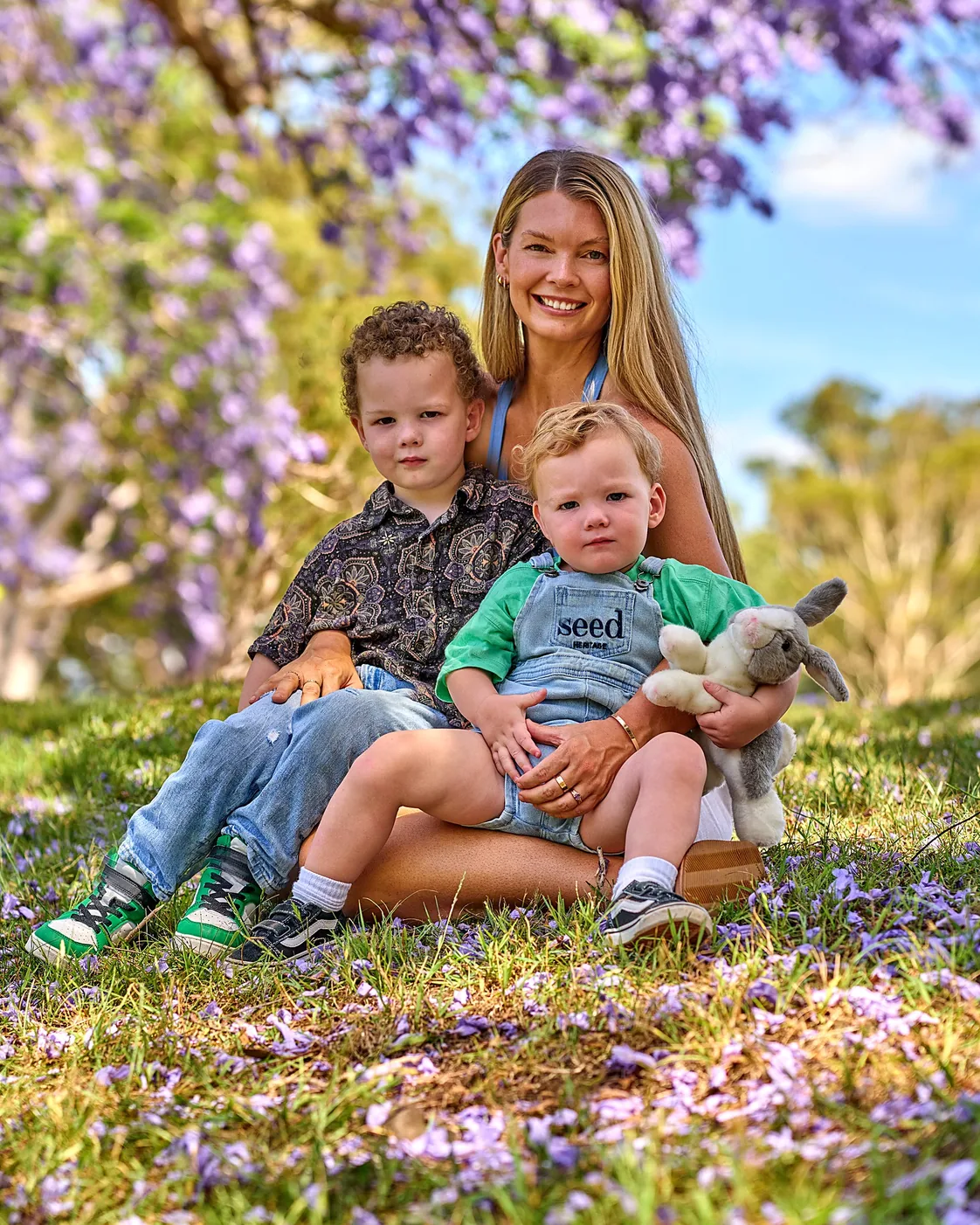 Emily Nowland sitting under a jacaranda tree with her two young sons
