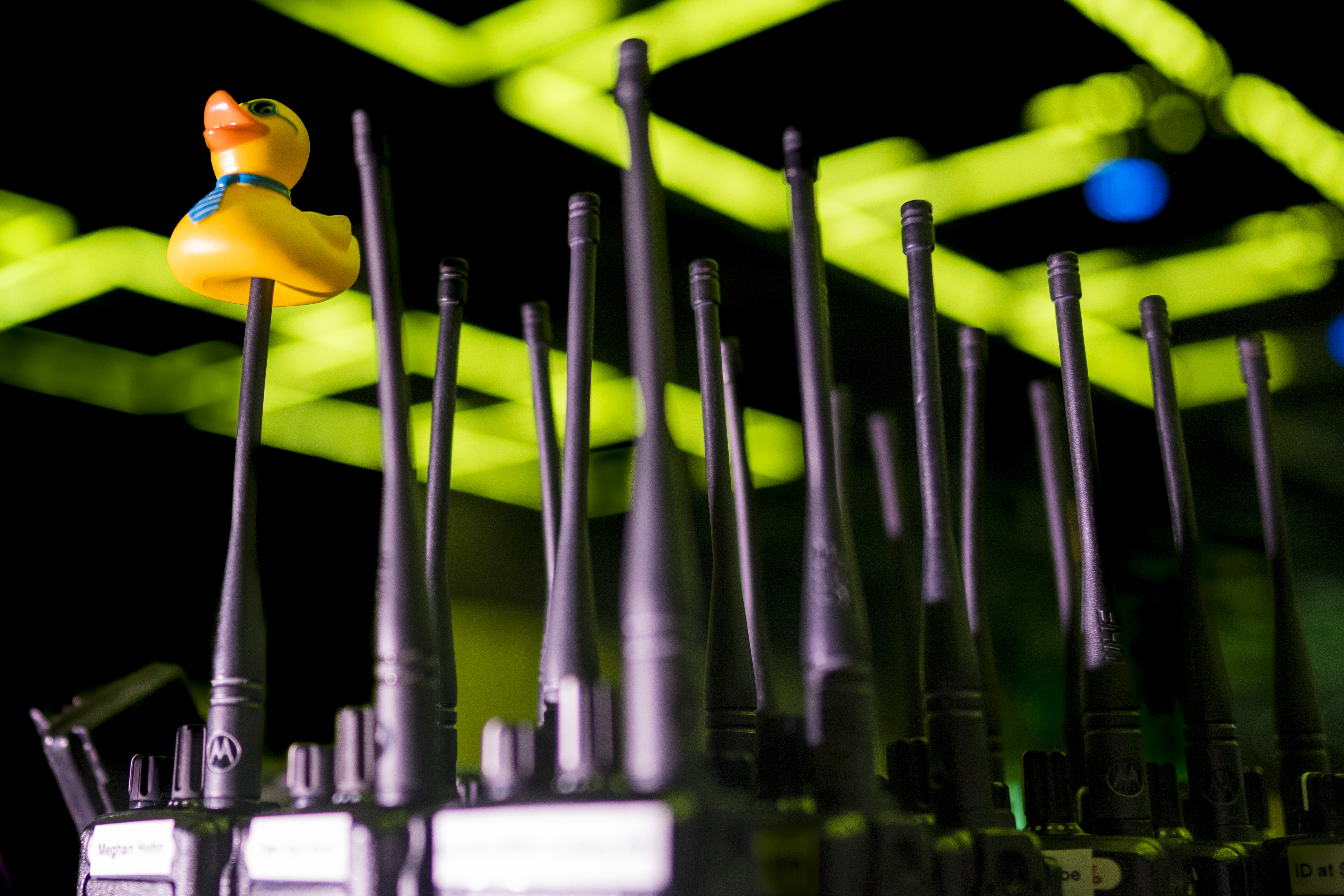 Rubber duck attached to one radio antenna among other radios with antennas under green lights.