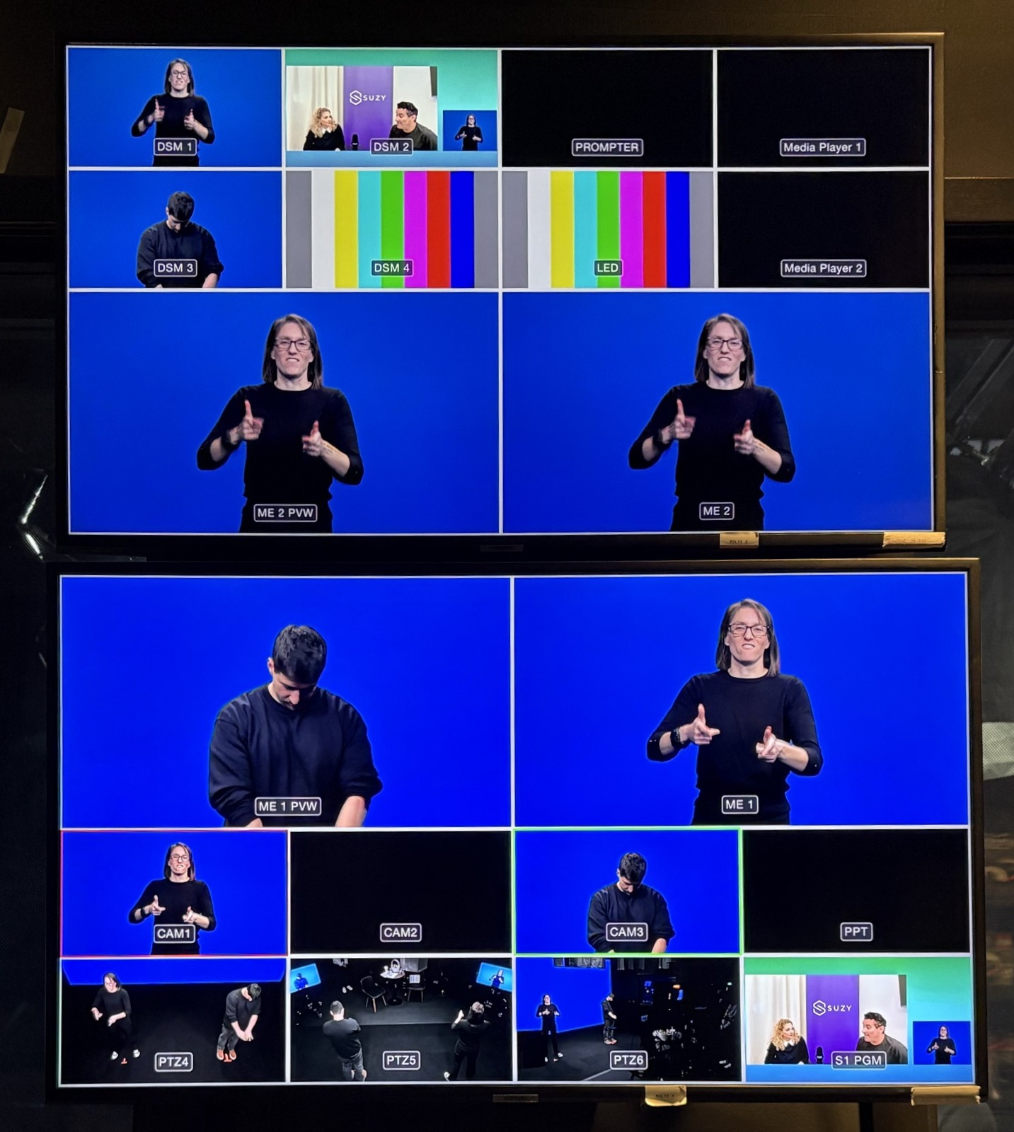 Two video monitor screens showing multiple camera feeds with sign language interpreters and studio scenes.