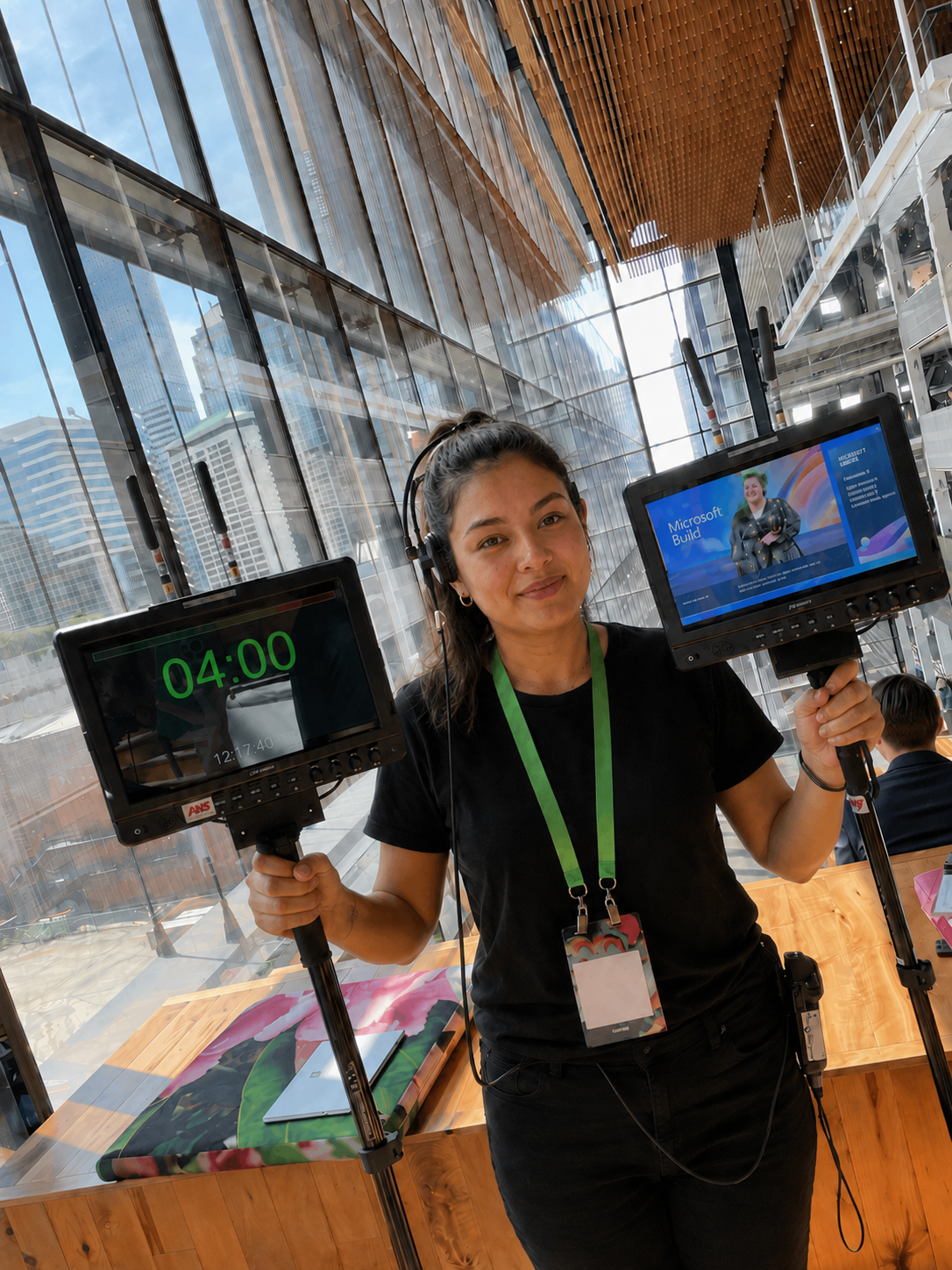 Woman in black shirt holding two screens, one shows timer 04:00, the other a Microsoft Build event.