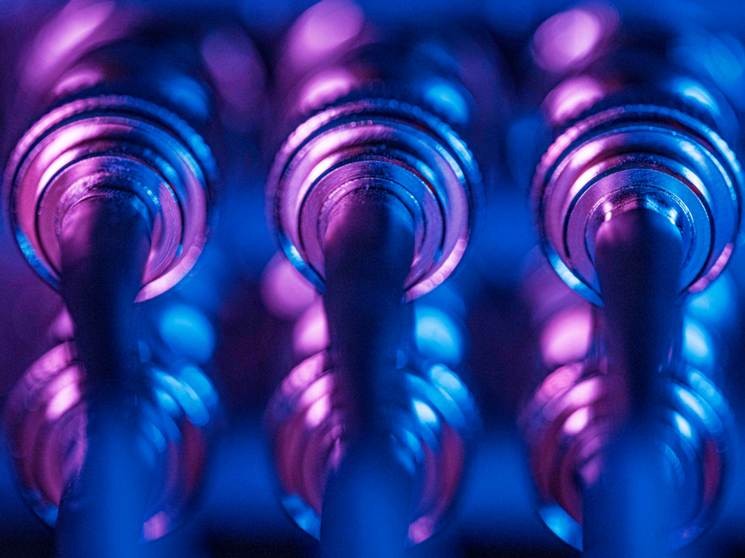 Close-up of three illuminated metal audio jacks with blue and purple lighting.