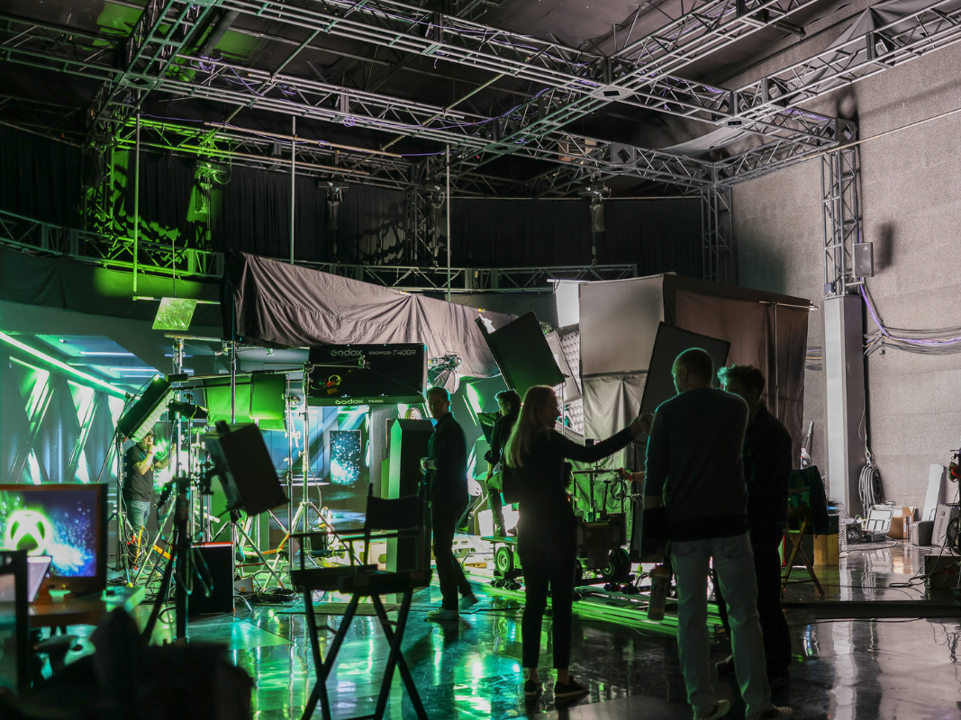 Silhouettes of people working on a film set with lighting and camera equipment.