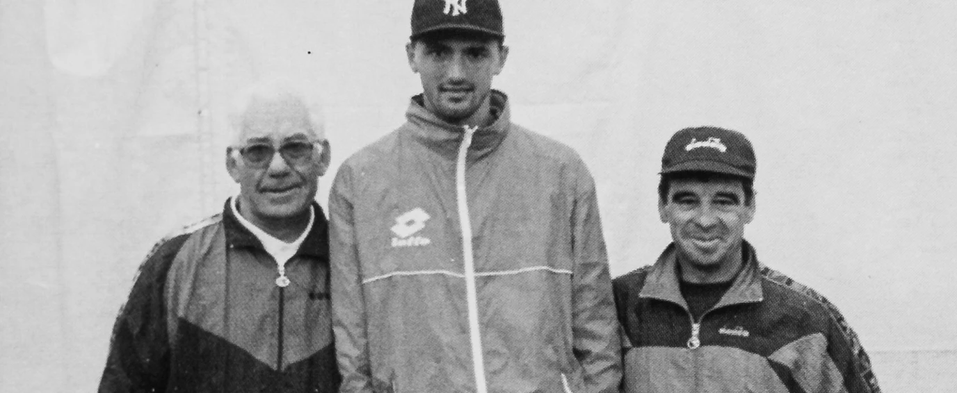 Black and white photo of three men standing side by side wearing jackets and caps.