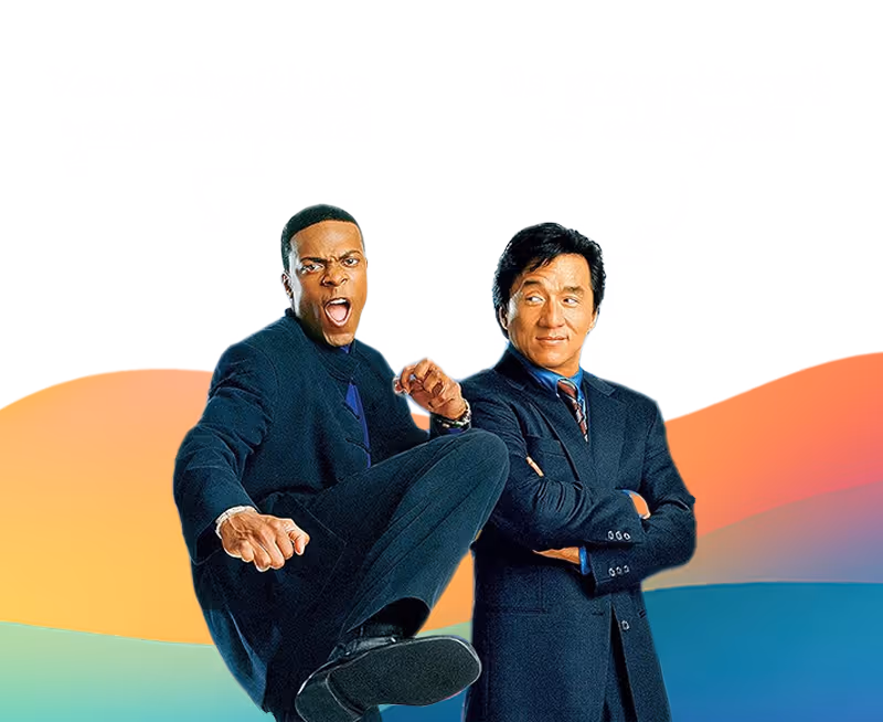 Two men in suits, one raising a fist and kicking forward, the other smiling with arms crossed.
