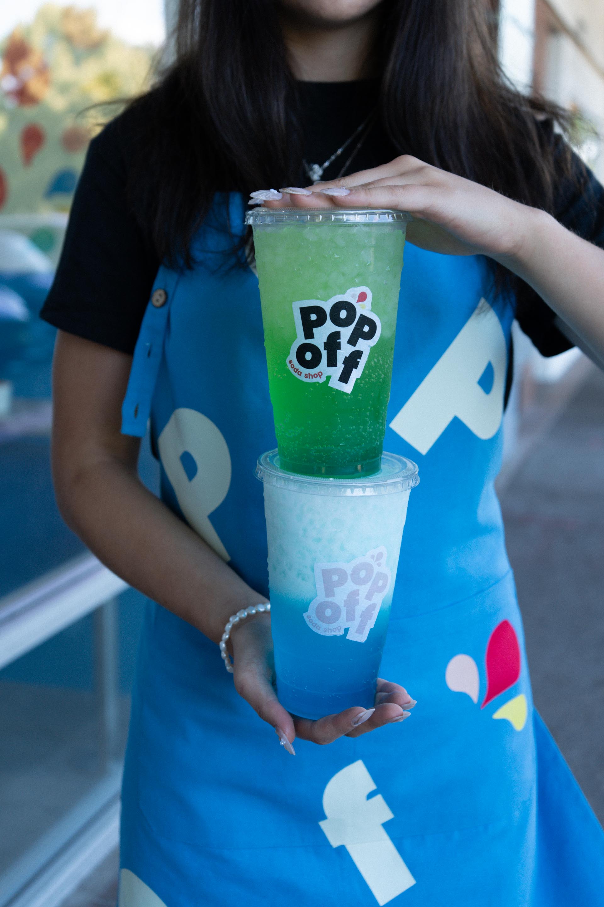 A person holding two drinks stacked on top of eachother